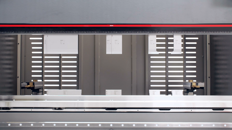 Close-up of a hydraulic bending machine bending metal sheets, showcasing the capabilities of a heavy-duty sheet metal bender in a workshop setting.