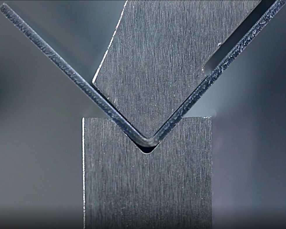 Close-up of a press brake bending sheet metal with precision - CNC press brakes in use.